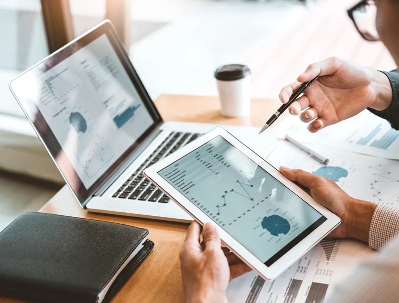 Charts and financial documents on a laptop and tablet